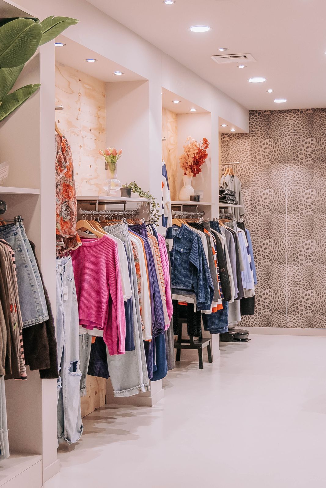 De winkel van KUIF aan de Klaasstraat: rekken met jeans, truien en jassen tussen houten wandkasten