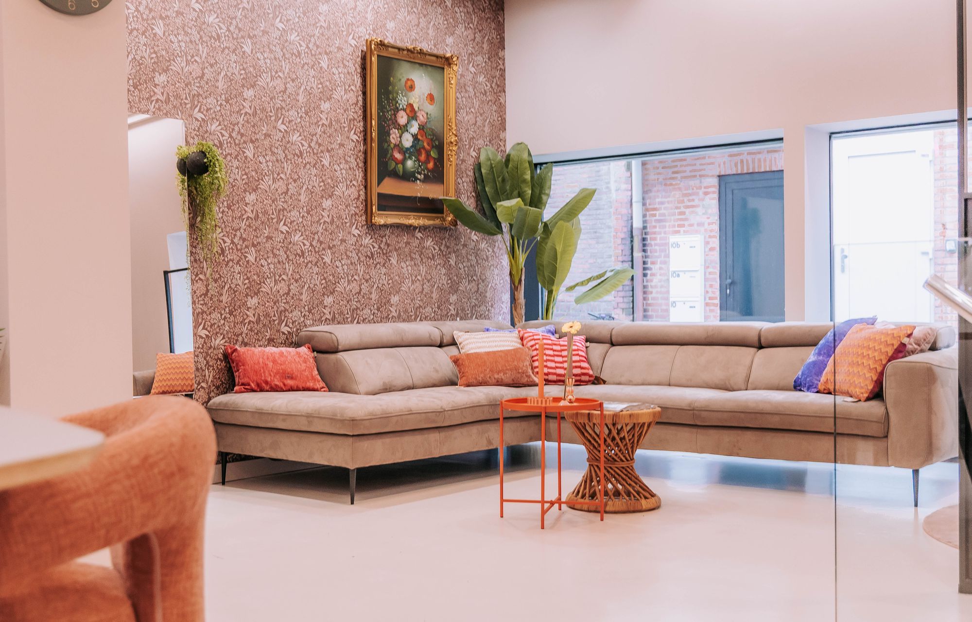 De huiskamer van KUIF: een lichte zithoek met hoekbank, kussens en een oranje bijzettafel