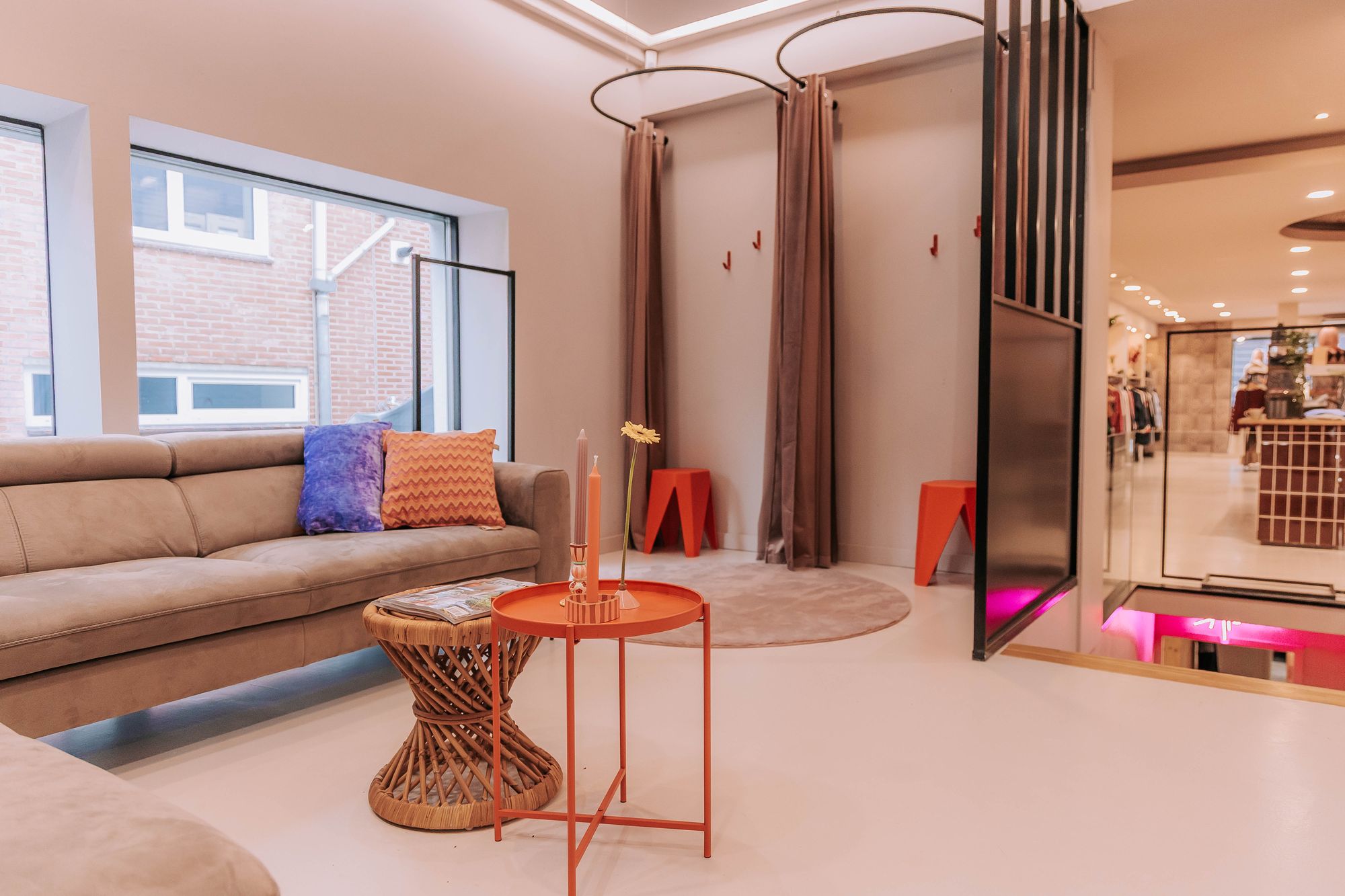De huiskamer van KUIF: een hoekbank, een ronde oranje tafel en de paskamers met gordijnen