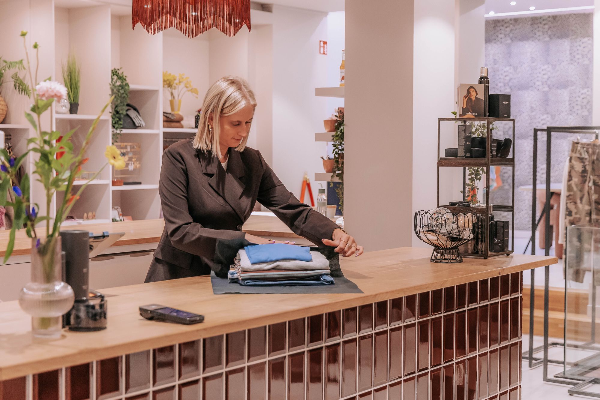 Semra pakt aan de toonbank van KUIF een stapel kleding in