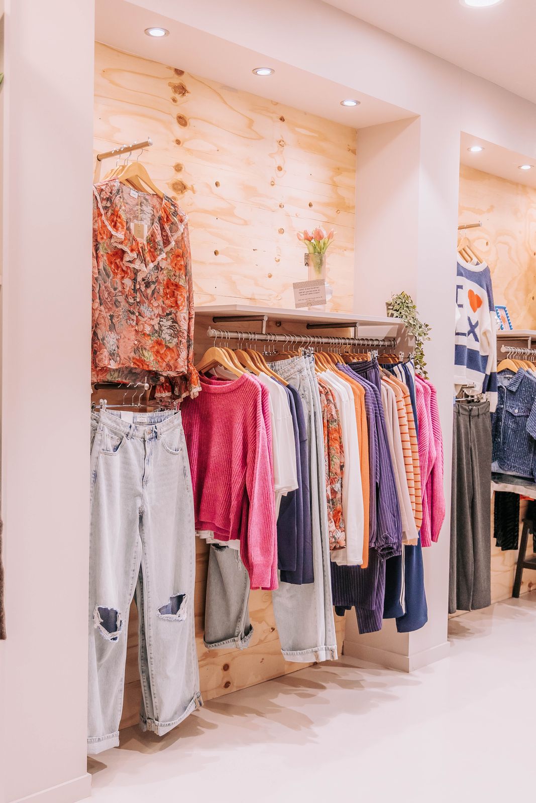 De rekken: een wand in de winkel van KUIF met truien, blouses en jeans op houten hangers